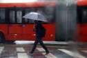 Pessoa andando na chuva com guarda chuva